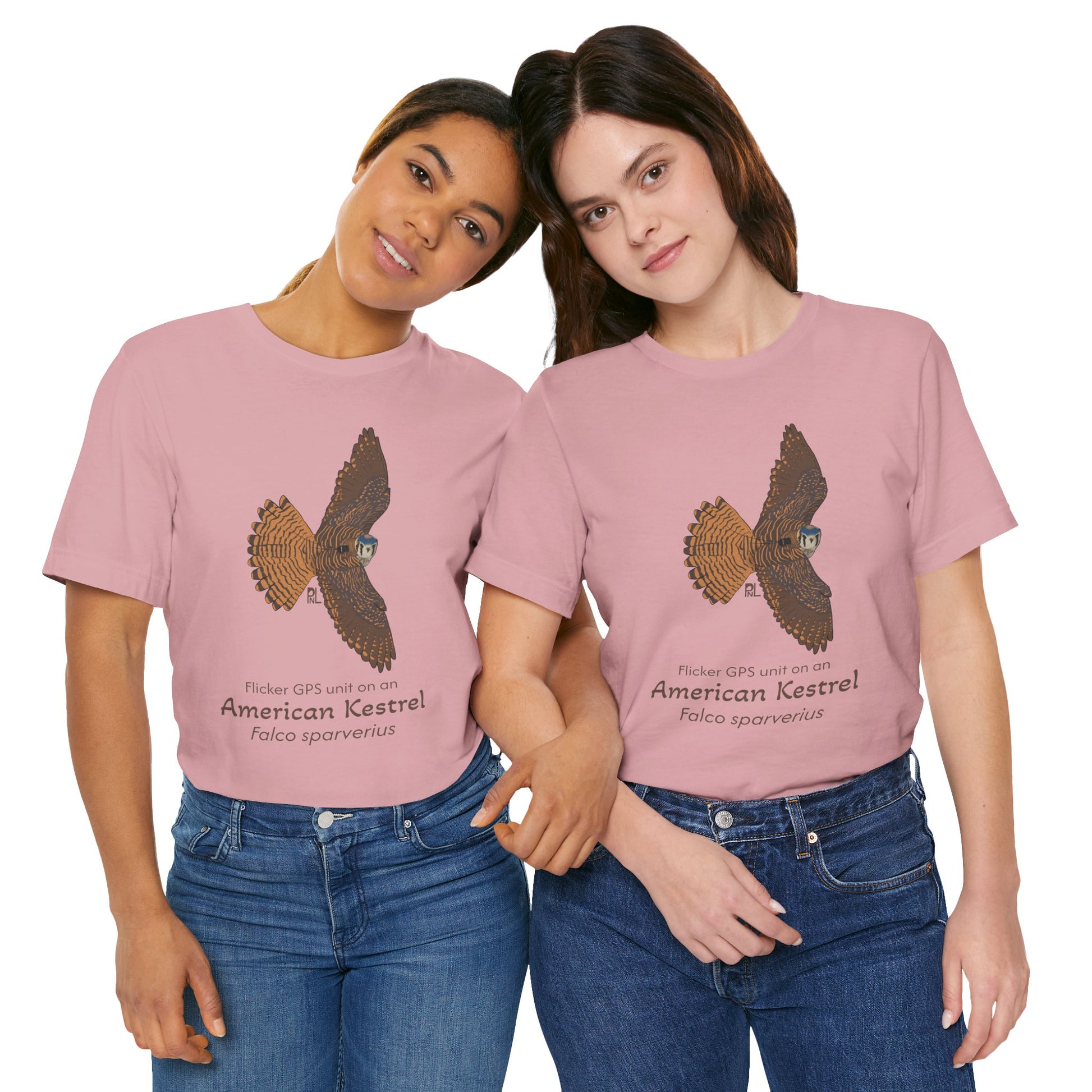 Two dark haired woman wearing pink t-shirts with an American kestrel illustration and text on a white background