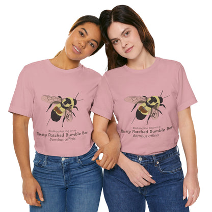 Two dark haired women wearing light pink t-shirts with a rusty patched bumble bee illustration and text on a white background