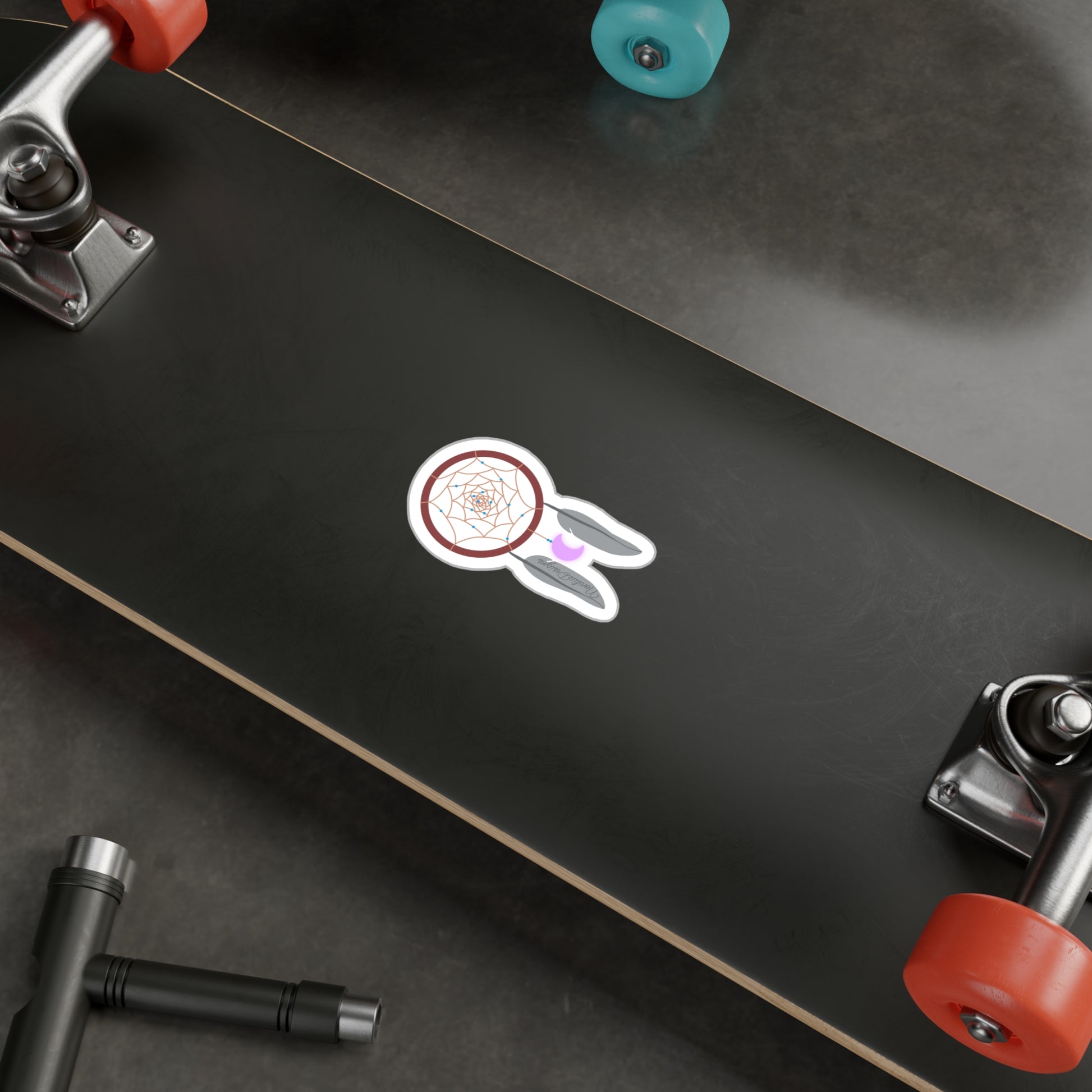 dreamcatcher sticker on the underside of a Skateboard with red wheels