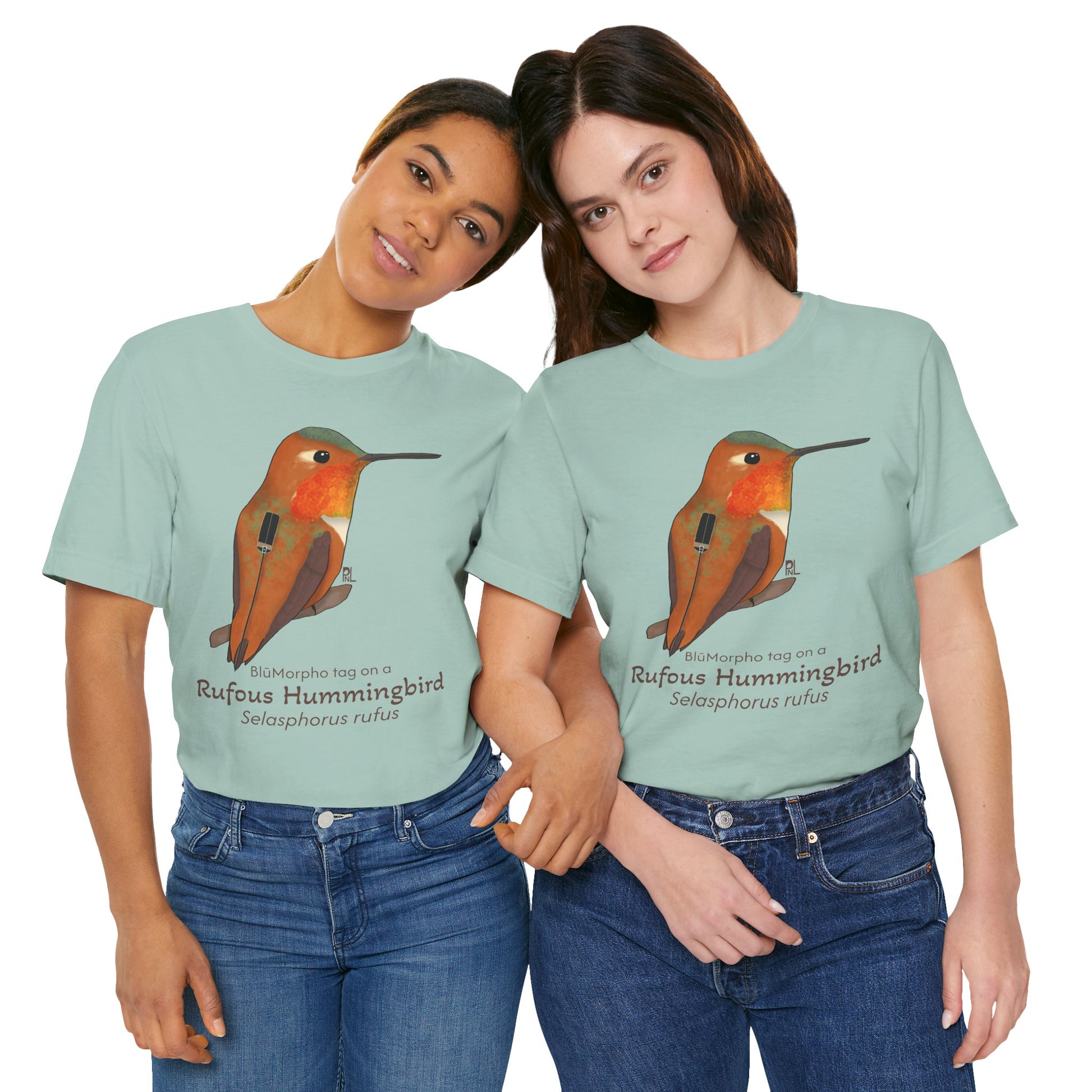 Two dark haired women wearing light blue-green t-shirts with a Rufous Hummingbird illustration and text on a white background