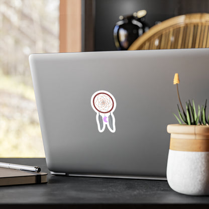Laptop with a sticker of a dreamcatcher on a desk with a plant and pen.