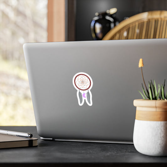 Laptop with a sticker of a dreamcatcher on a desk with a plant and pen.