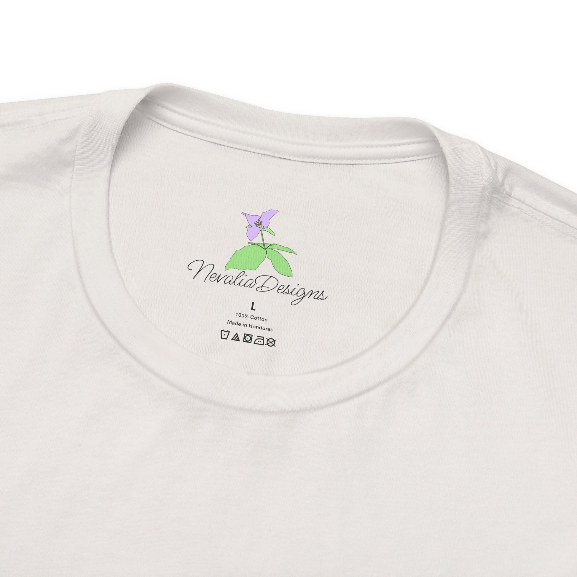 White t-shirt inner neck label with a small logo, featuring a purple flower and 'Nevalia Designs' text.