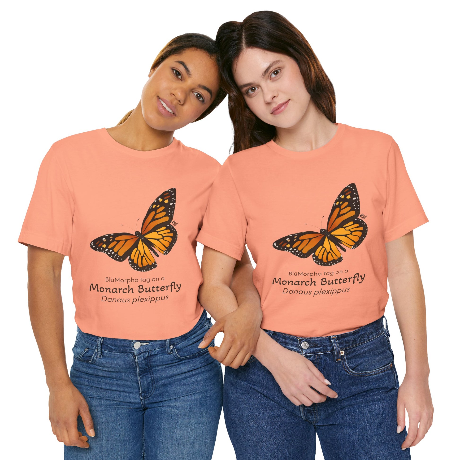 Two dark haired women wearing peach t-shirts with a monarch butterfly illustration and text on white background