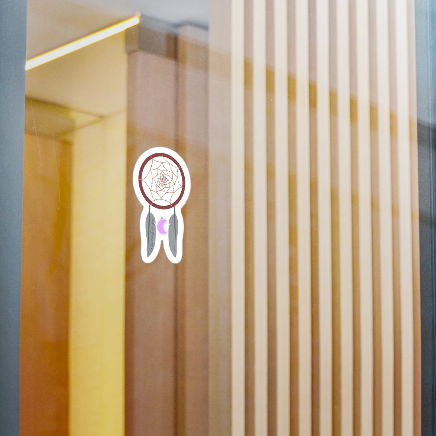 dreamcatcher sticker on a glass surface with vertical blinds in the background.