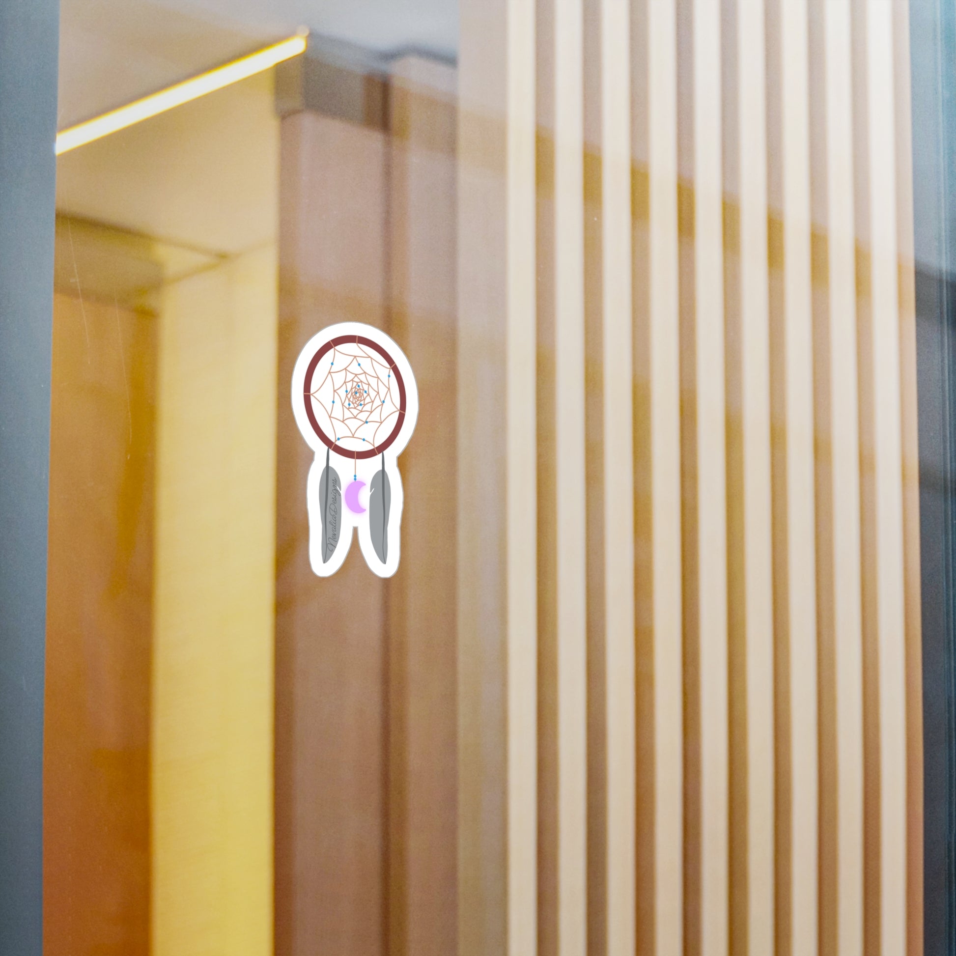 dreamcatcher sticker on a glass surface with vertical blinds in the background.