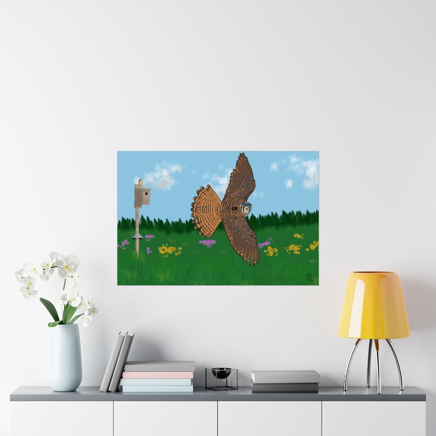 A poster of an American Kestrel flying over a field with flowers and a nest box with a blue sky and forest on a white wall above a shelf with decor items.
